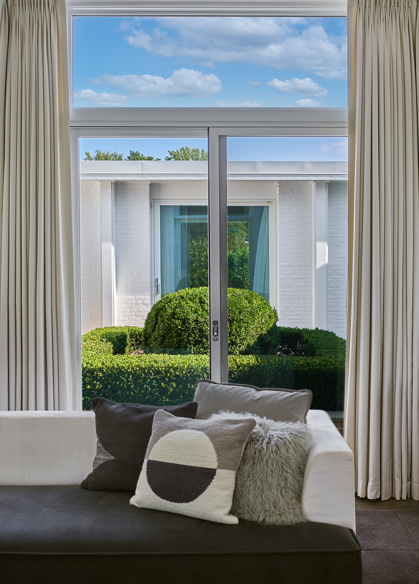 Interior designed black and white modern couch with black and white decorative pillows. Neutral curtains on sliding glass doors