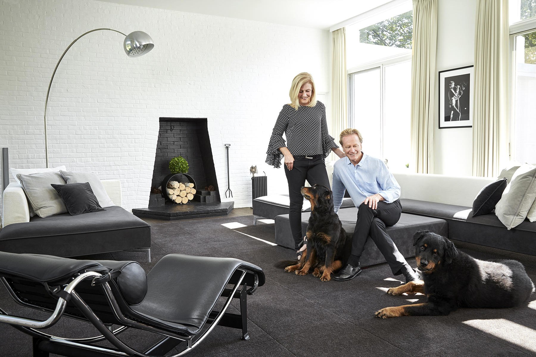 Anthony and Liz wilder with their dogs in their modern black and white living room. Modern black and white wood burning fireplace