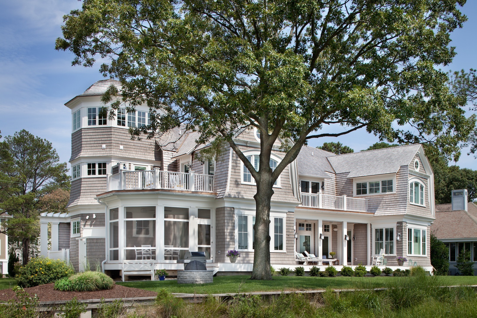 Back exterior of a custom built coastal beach house with a silo and screened in porch attached