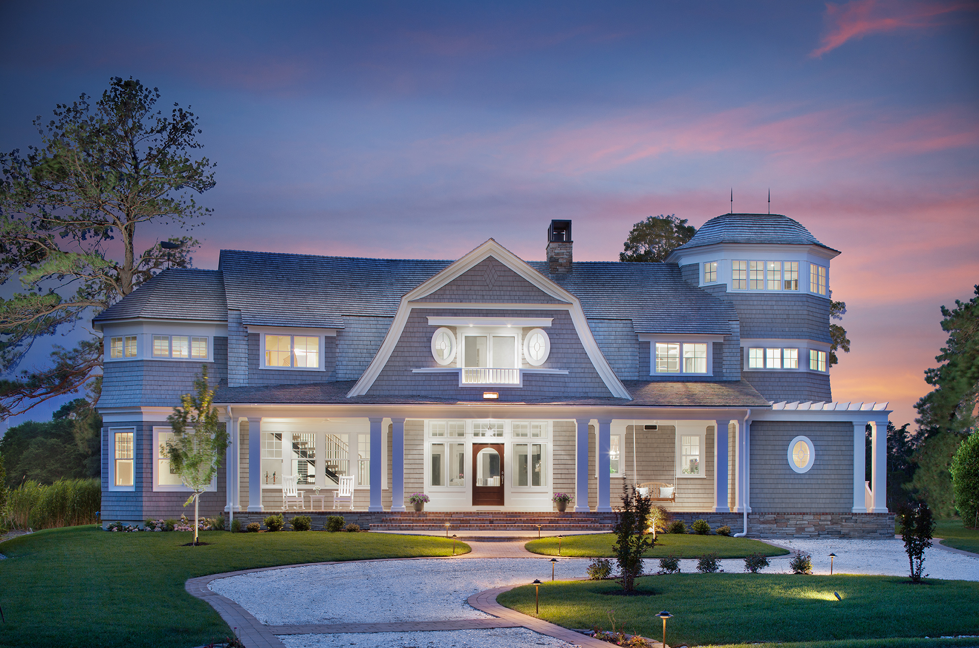 Front exterior of a coastal beach house with square front pillars on the front porch, tons of front windows and natural light