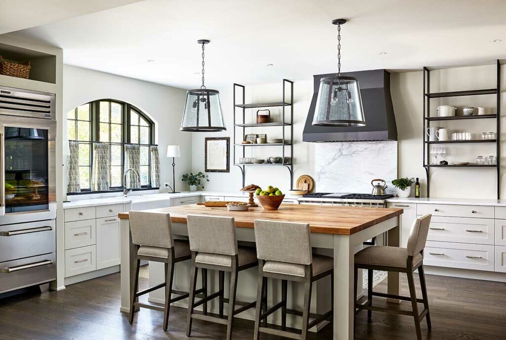 modern take on a French country kitchen with a large island featuring a butcher block wood countertop and seeded glass pendants with oil rubbed bronze accents