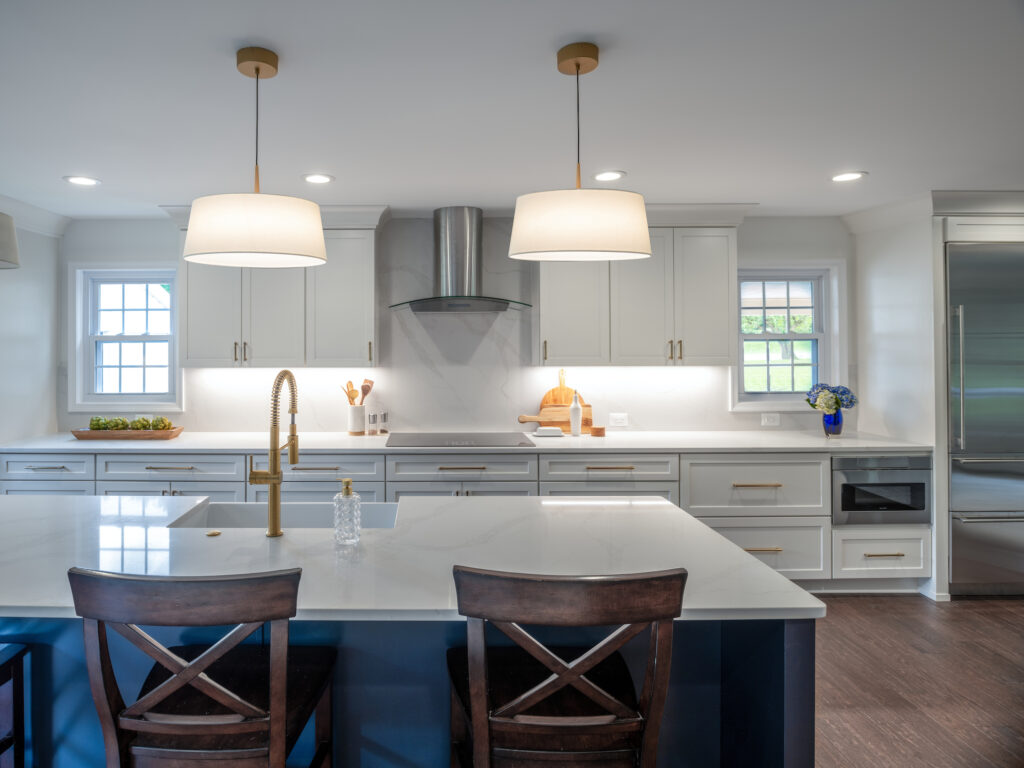 Wide open kitchen with white quartz countertops, brushed gold fixtures and a steel range hood